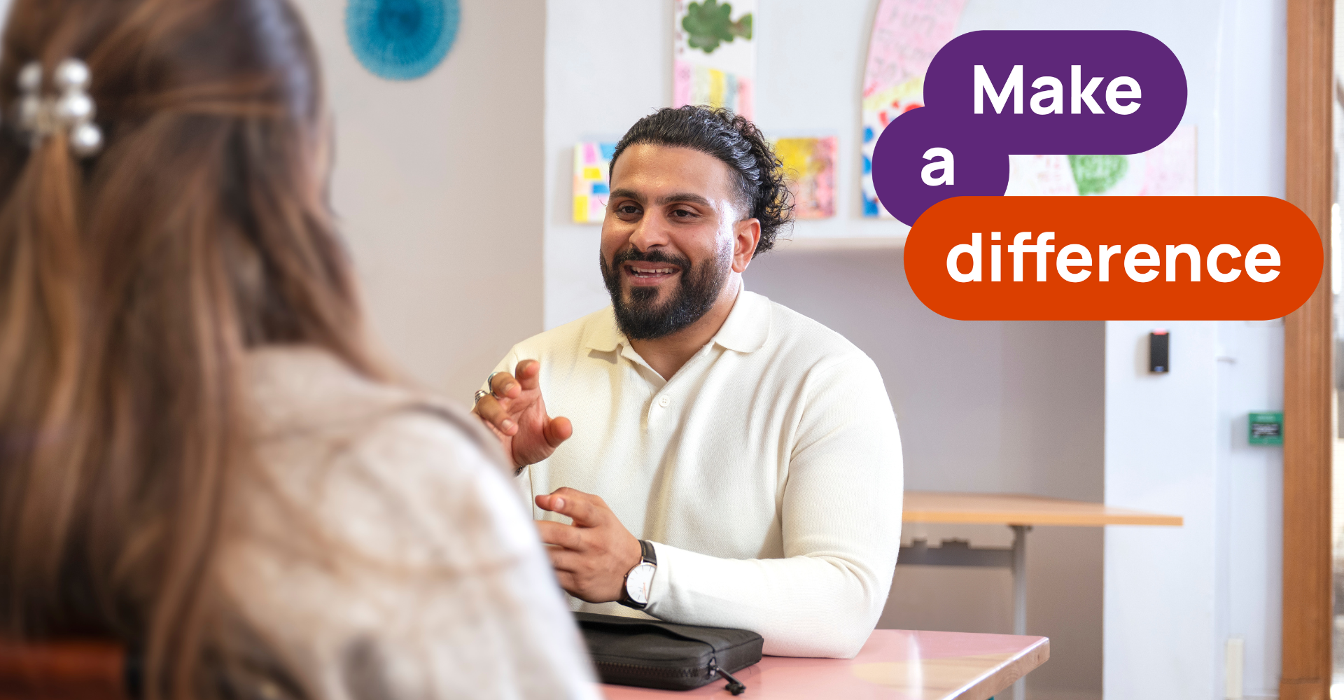 Man with beard smiling sitting at table with woman opposite. Make a difference